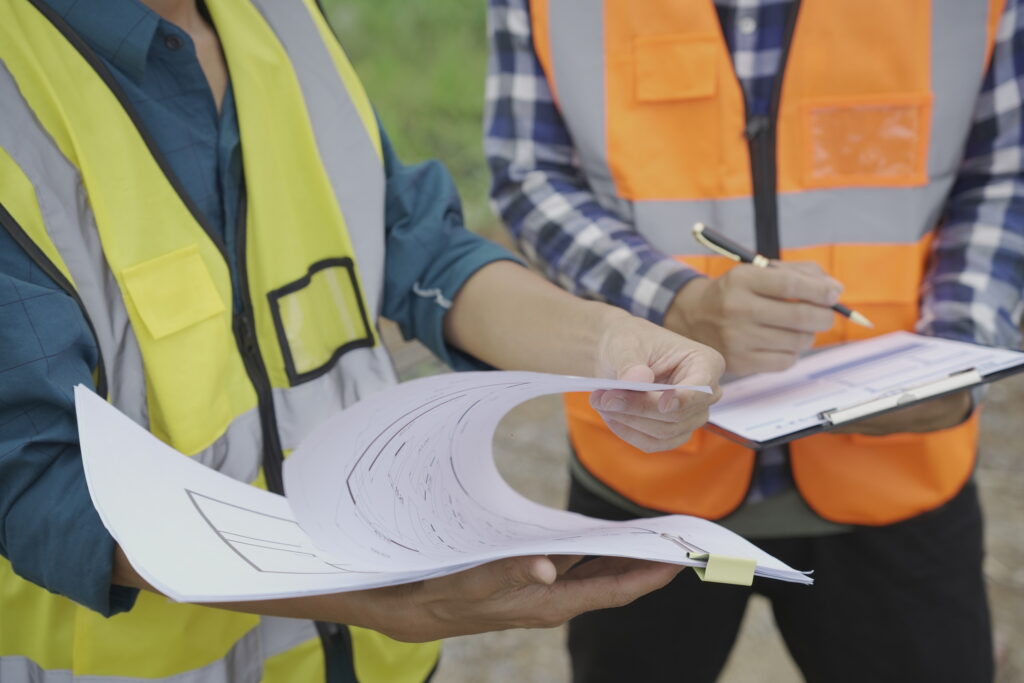 Professional architect engineer with hard hat and blueprint at building construction site house building permit background. Architects looking at blueprints. Construction and engineering industry